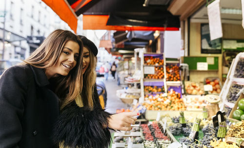 Smiling young woman looking at store in market