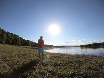 Rear view of man standing on shore against sky