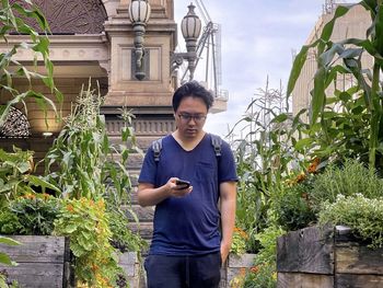 Portrait of young man standing against plants