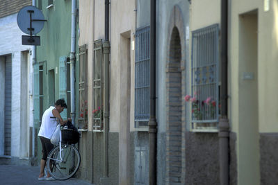 Side view of woman sitting on building in city