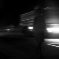 Rear view of person walking on illuminated street at night