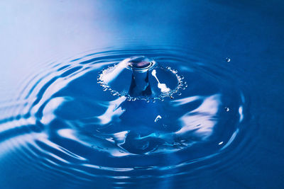 Close-up of drop falling on blue water