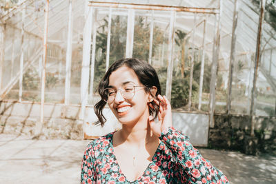 Portrait of young woman standing against trees