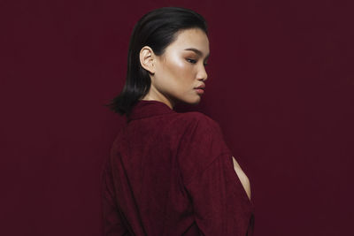 Young woman looking away against gray background