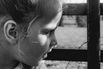 Close-up of girl looking away by fence