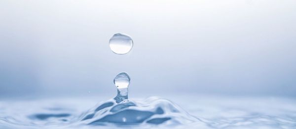 Close-up of water drop against blue sky