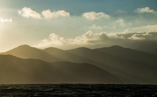 Scenic view of sea and mountains against sky