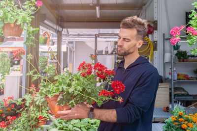 Man holding flower pot standing by potted plants