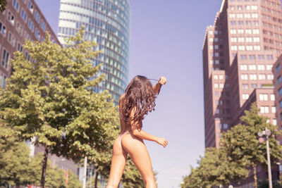 Young woman wearing bikini while standing against buildings in city