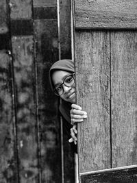 Portrait of woman standing against door