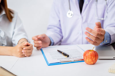 Midsection of woman with tattoo on table