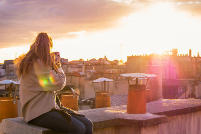 Rear view of woman sitting on rooftop