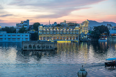 River by buildings against sky at sunset