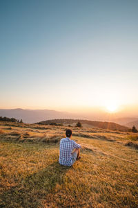 Man in shirt watching sunset. soaking up positive energy and relieving stress