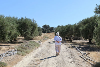 Rear view of woman walking on dirt road