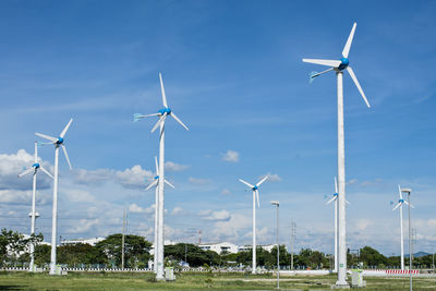 Wind turbines on field against sky