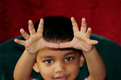 Portrait of boy gesturing while sitting on chair