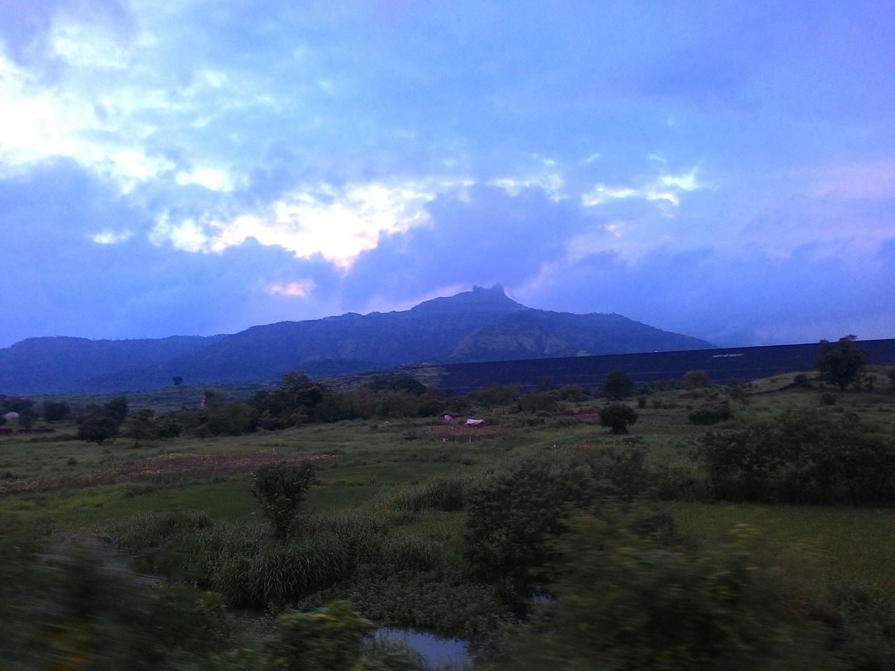 COUNTRYSIDE LANDSCAPE AGAINST MOUNTAINS