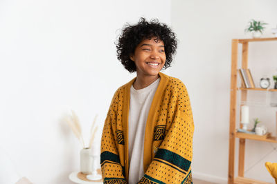 Portrait of young woman standing against wall