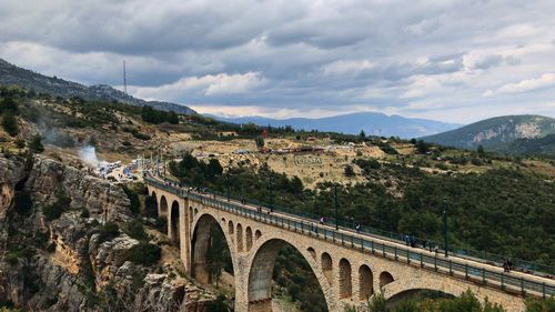 Arch bridge over mountains against sky