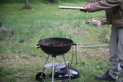 Low section of man standing by barbecue grill