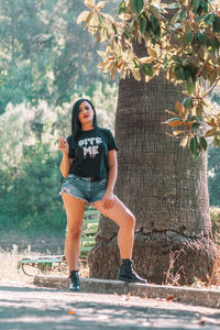 Full length portrait of young woman against plants