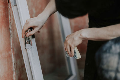 Caucasian guy cleans window frames with a construction knife.