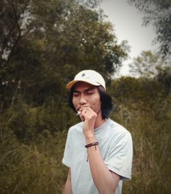 Man looking away while standing against plants