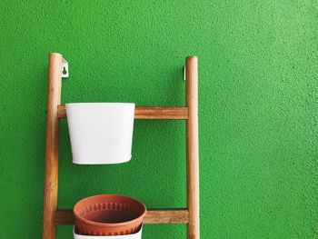 Close-up of chairs on table against green wall