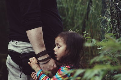 Father and daughter walking by plants at forest