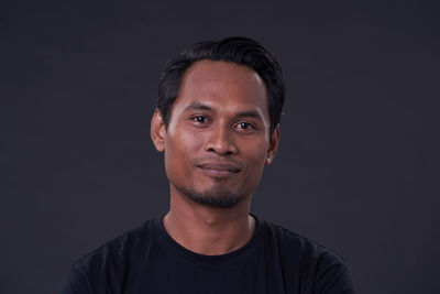 Portrait of young man against black background