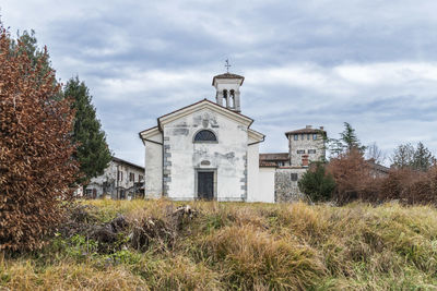 Church on field by building against sky