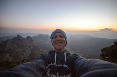 Portrait of cheerful man on mountain against sky during sunset