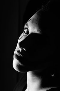 Portrait of thoughtful young woman against black background