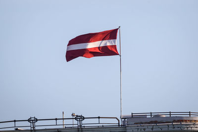 Flag of latvia waves on rooftop.
