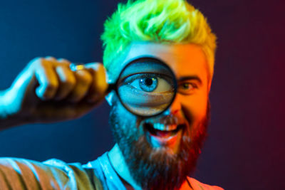 Portrait of man looking through magnifying glass