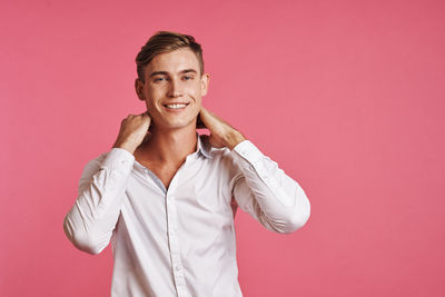 Portrait of smiling young man against pink background