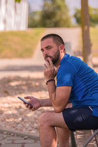 Man using mobile phone while sitting outdoors