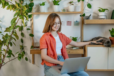 Young woman working on laptop at home. cozy home office workplace, remote work or learning concept.