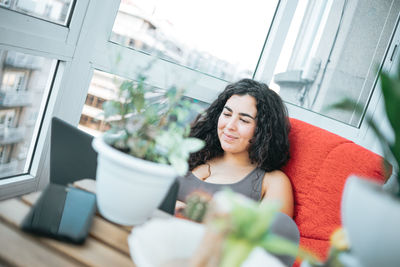 Portrait of young woman sitting on sofa at home