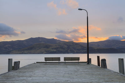 Pier amidst mountains against sky during sunset