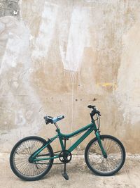 Side view of bicycle parked against wall