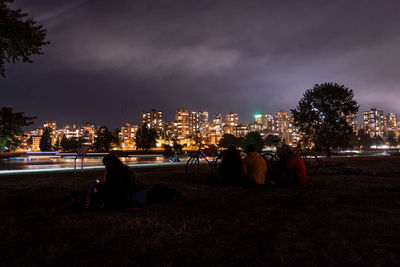 People sitting on illuminated street at night