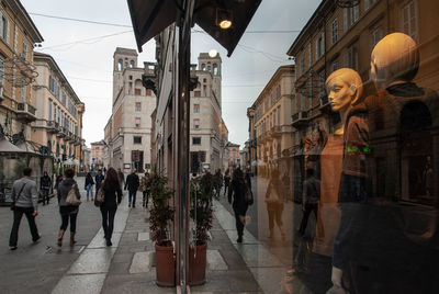 People walking on street amidst buildings in city