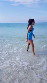 Full length of woman standing at beach against sky