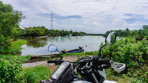 Bicycle by river against sky