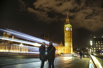 Illuminated clock tower in city at night