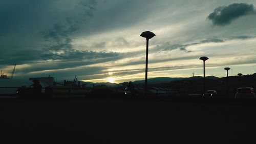 Silhouette street against sky at sunset