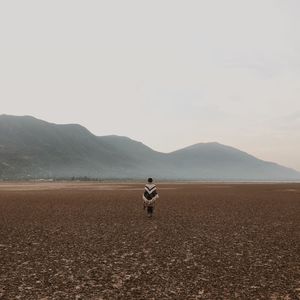 Rear view of woman standing on field against mountains