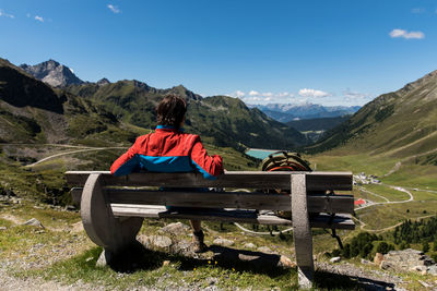 Rear view of man looking at view while sitting on bench